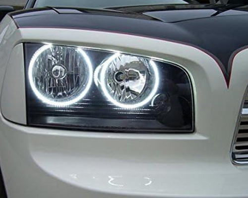 Close-up of a dodge charger headlight showcasing a bright white forward-facing LED halo ring against a dark background.